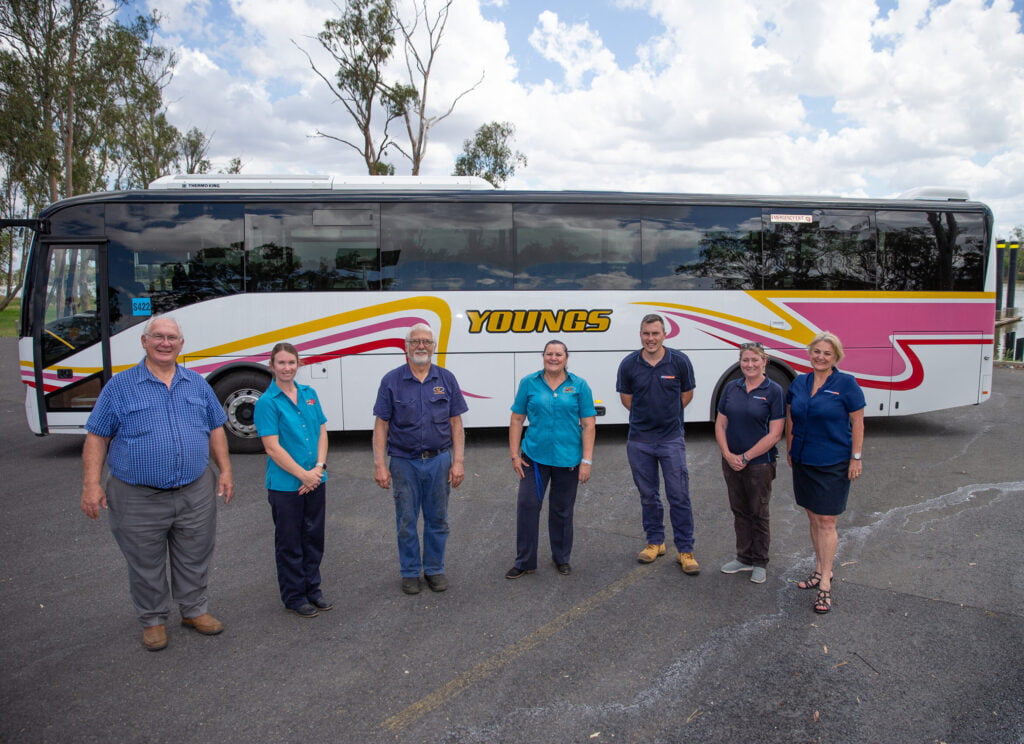 Young's group staff standing in front of a bus